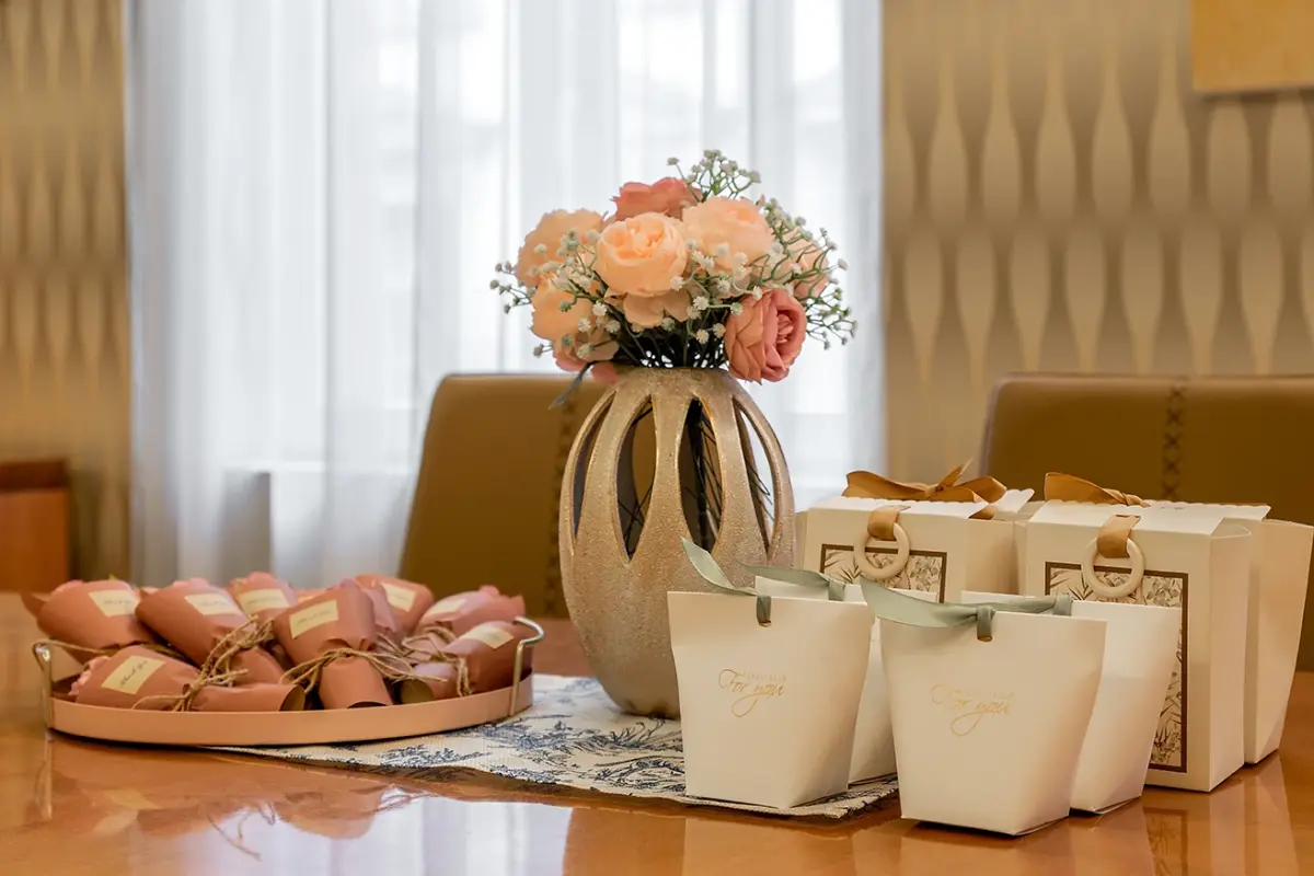 Roses in a vase beside wrapped gifts on a table