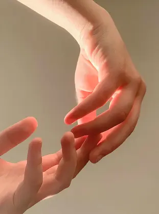 Two hands almost touching in warm light