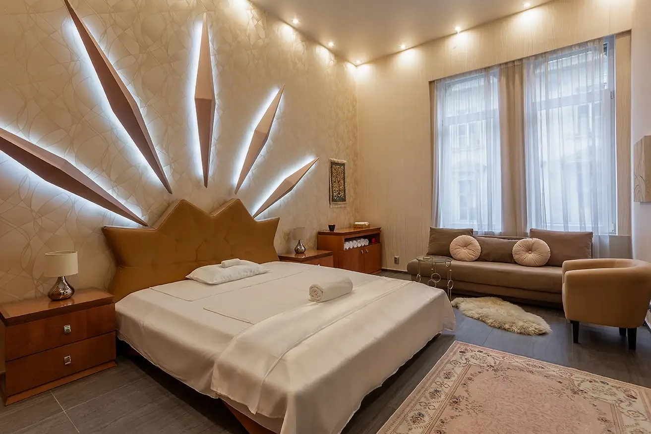 Suite with sun-ray wall lights, bed and sofa by tall windows